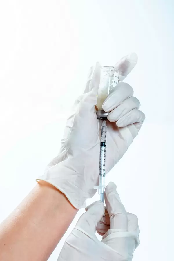 The doctor takes the medicine in a syringe from the bottle