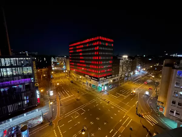 The empty building at Friesenplatz in Cologne lit by temporary installation with heart and cross by studio polylog