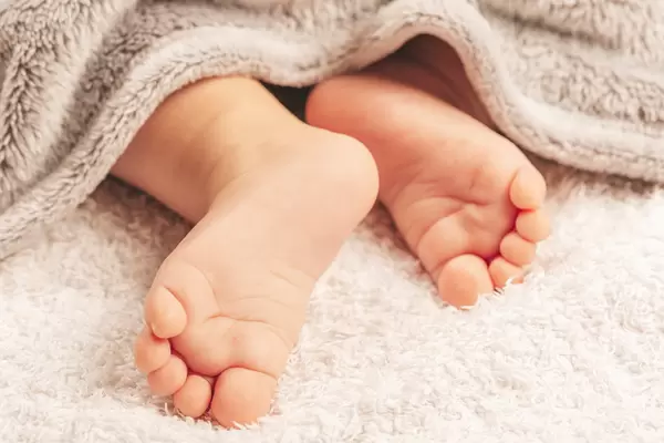 The feet of a small child are visible from under the blanket. Family values concept