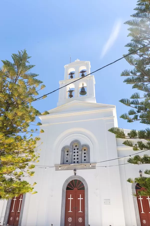 The front of the church of Panagia Protothronos in Halki, Naxos, with reddish-brown doors, four bells