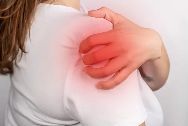 The girl holds her hand on her shoulder, the concept of pain