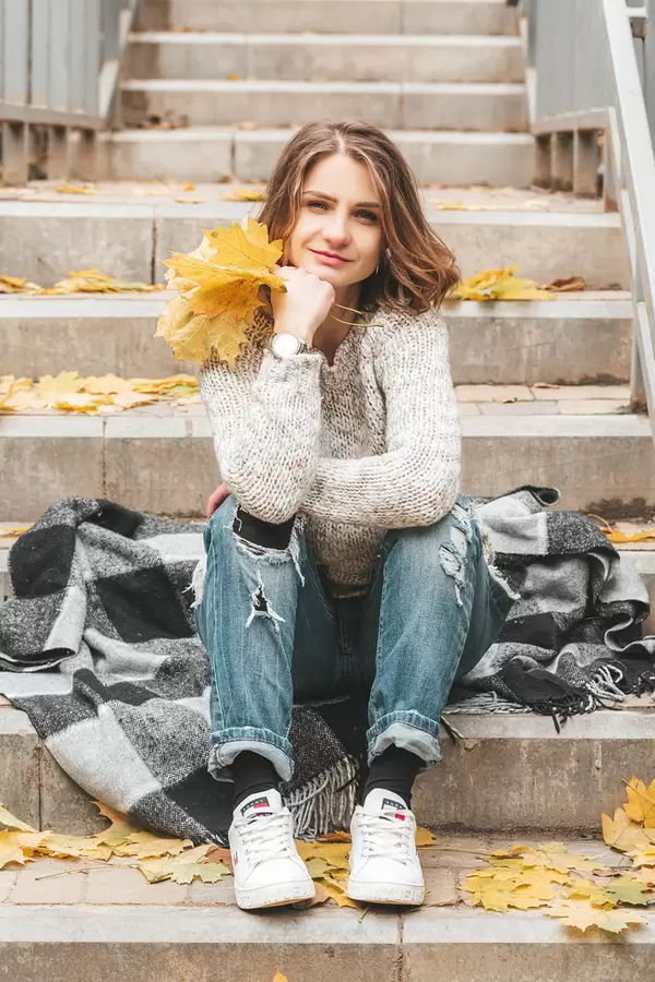 The girl is sitting on the steps and smiling, autumn walk