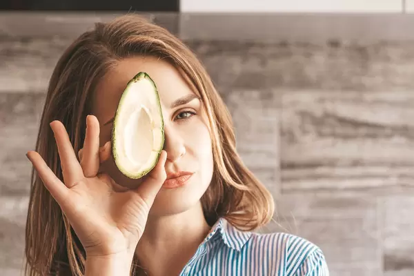 The girl with half a fresh avocado in front of her face
