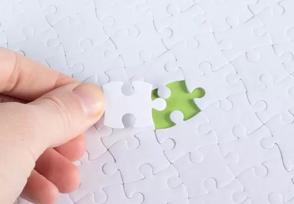 The human hand fills the last missing elements of the surface from the jigsaw puzzle. The concept of the completion of the initiated cases