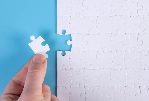 The human hand fills the last missing elements of the surface from the jigsaw puzzle