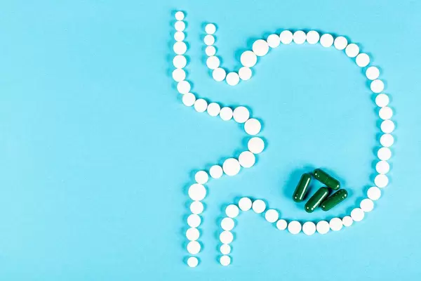 The human stomach of tablets on blue with green capsules
