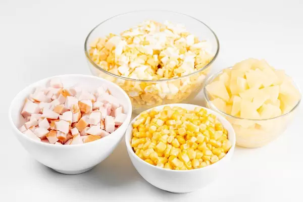 The ingredients in a glass bowl to prepare the salad with smoked chicken and pineapple