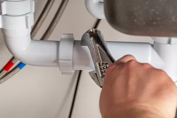 The plumber makes measurements of the diameter of the pipe using an adjustable wrench, close-up