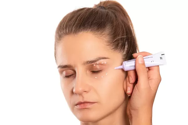 The process of applying cream around the eyes, taking care of the skin of the face