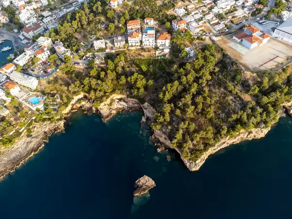 The stunning rocky coast of Alonnisos in a drone image with houses, hotels, trees and the blue sea