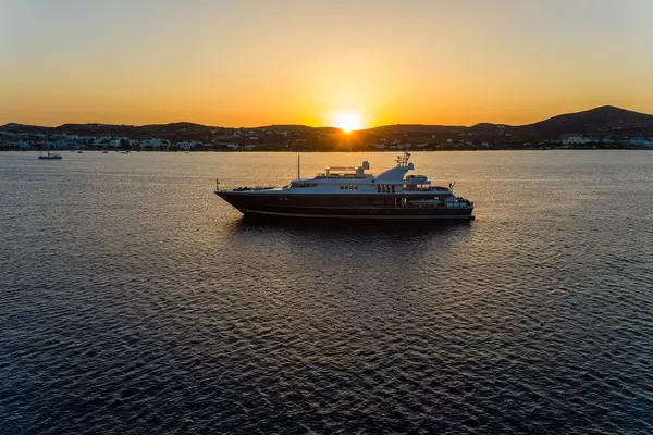 The sunset at the port of Adámas, Milos, Greece. The sea, a yacht and the sun setting behind the island