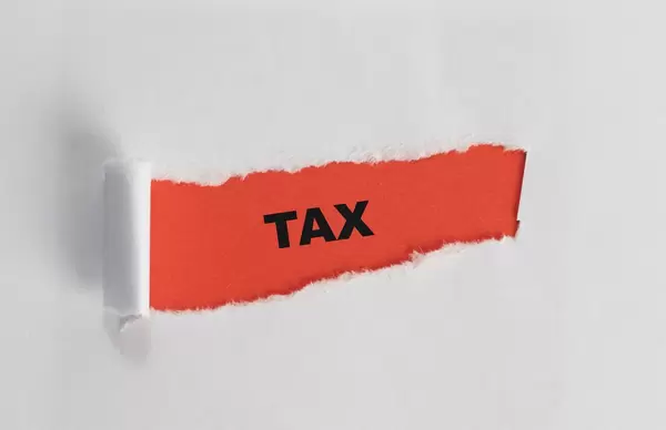 The text Tax appearing behind torn white paper