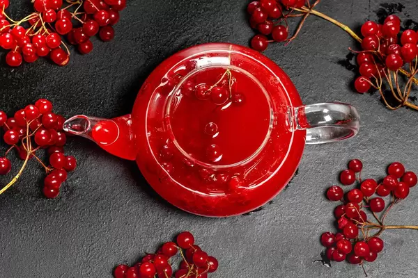 The view from the top glass kettle with fresh berries of viburnum on a black background