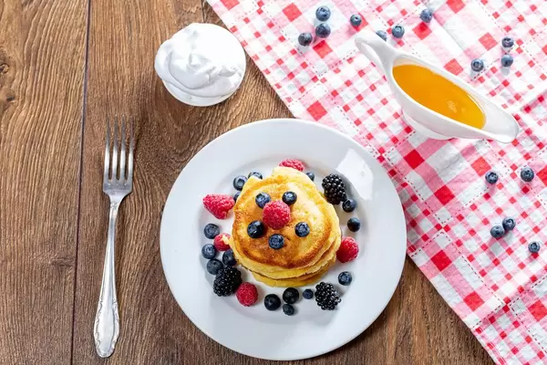 The view from the top the pancakes with fresh berries, honey, and cream with a fork. The concept of Breakfast (Flip 2019)