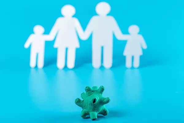 The virus is made from plasticine on a blue background with a silhouette of a family behind