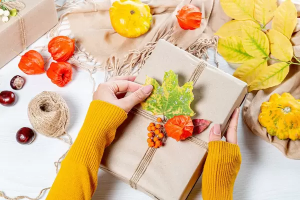 The woman wraps a gift at thanksgiving on autumn background (Flip 2019)
