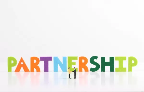 The word Partnership with two businessman shaking hands on white background