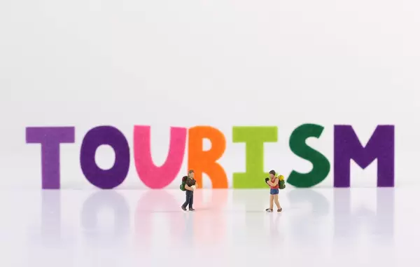 The word Tourism with two travelers on white background