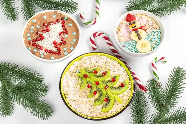 Three bowls of decorated oatmeal on christmas background