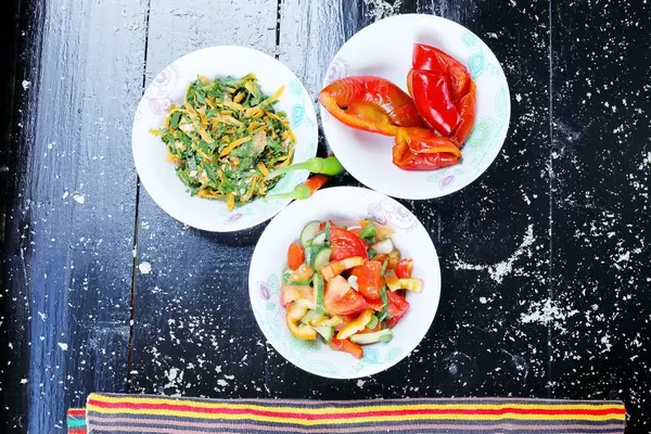 Three bowls of salad: pickled peppers, fresh vegetables and carrots salad. Black background (Flip 2019)