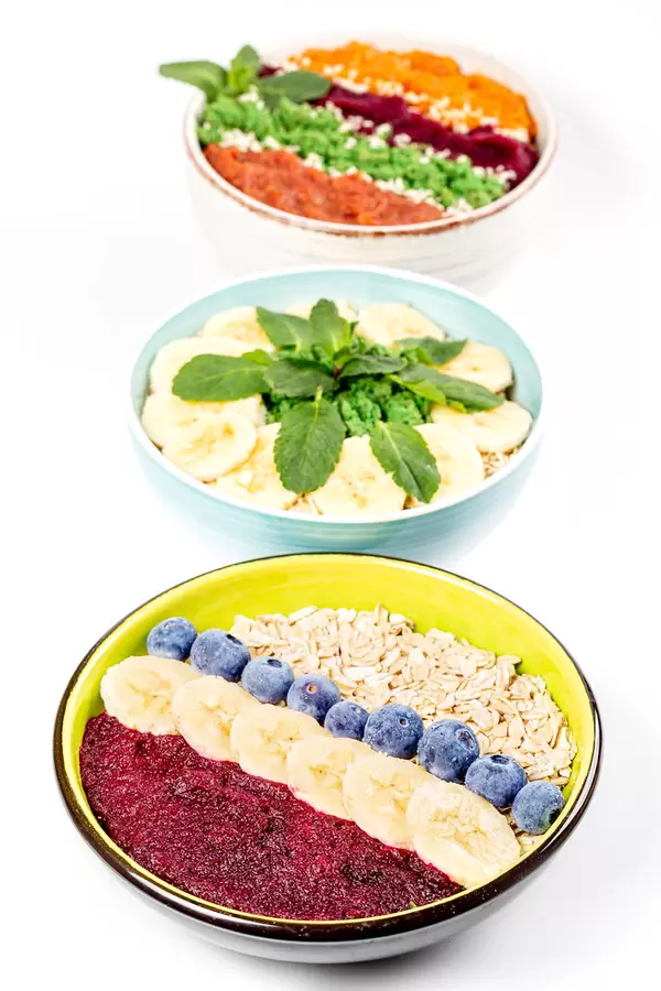 Three bowls with oatmeal and fruits on white