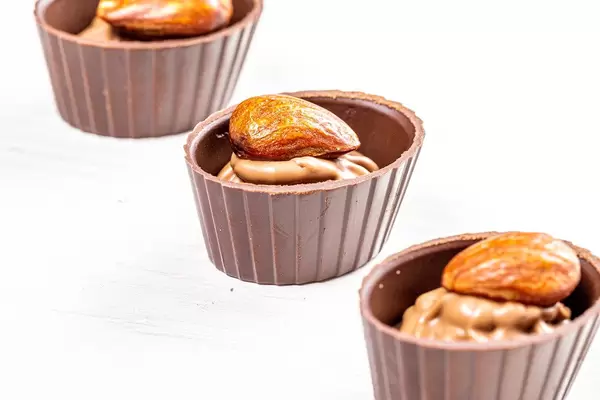 Three chocolates with whole almonds on white wooden background (Flip 2019)