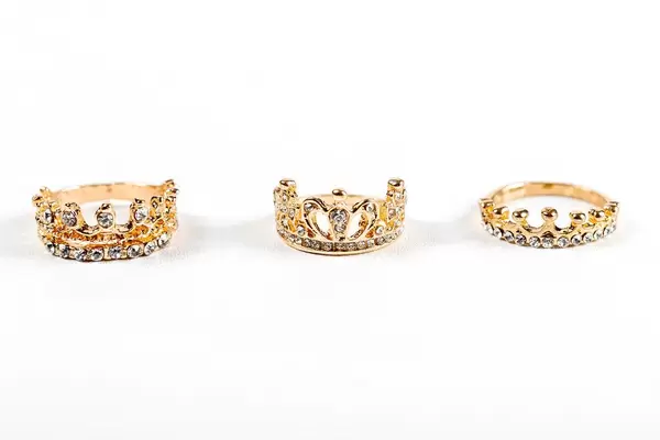 Three crown-shaped rings with stones on a white background