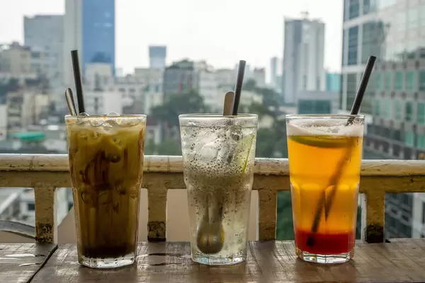 Three different Cold Drinks with Plastic Straws on a Balcony with a View of Ho Chi Minh City, Vietnam in the Background