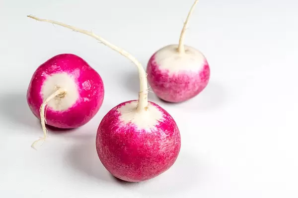 Three fresh radishes on a white background