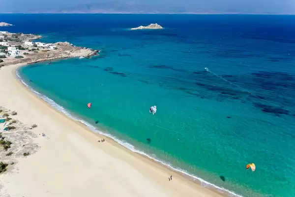 Three kites flying in the wind on the empty beach of Mikri Vigla on the Greek island of Naxos. Aerial view