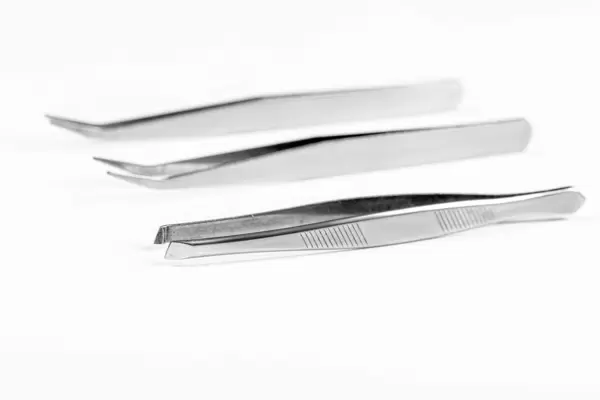 Three metal tweezers on a white background
