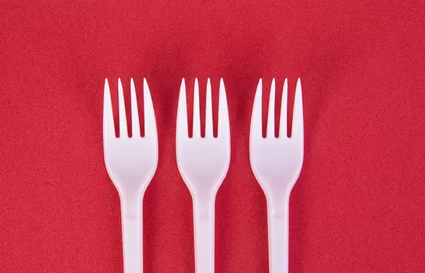 Three plastic forks on red background