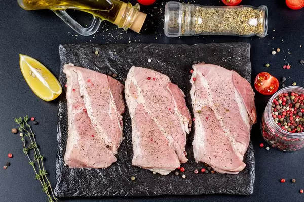 Three-raw-steaks-with-ingredients-on-a-black-background-top-view.jpg