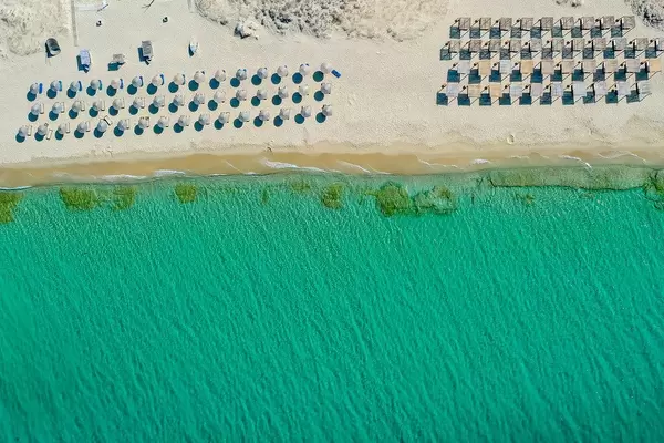 Three rows of round thatched beach umbrellas and four rows of square sunshades. Plaka beach, Naxos