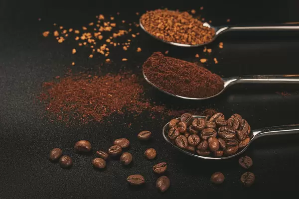 Three spoons of coffee with Soluble coffee, coffee beans and ground coffee on dark background
