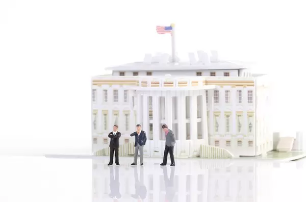 Three suited businessman standing in front of White House