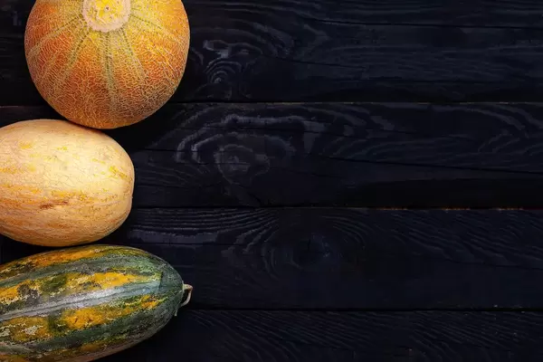 Three sweet melons on the dark board