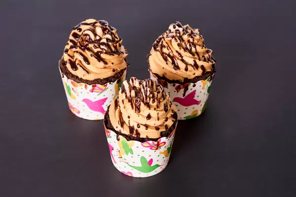 Three tasty caramel cupcakes dark surface