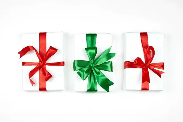 Three white X-mas gifts with red and green textile ribbon on white background