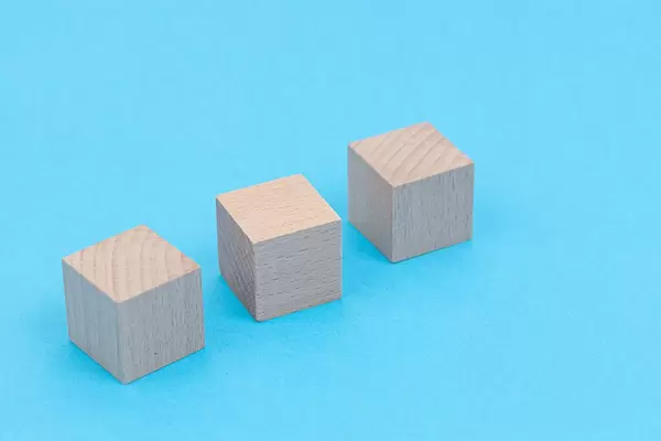 Three Wooden Cubes above blue background with copy space