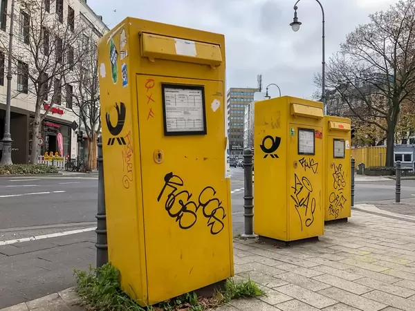 Three yellow mailboxes of the German post painted with graffiti at intersection