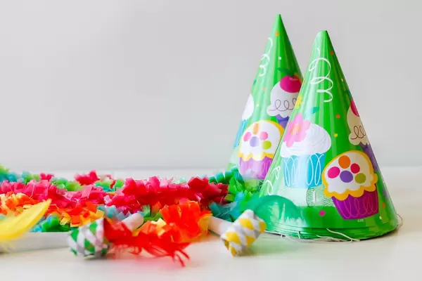 Time to party: green cone hats, whistles and garlands on a white background
