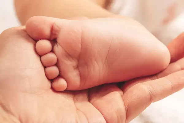Tiny baby's feet on female hand closeup. Mom and her child