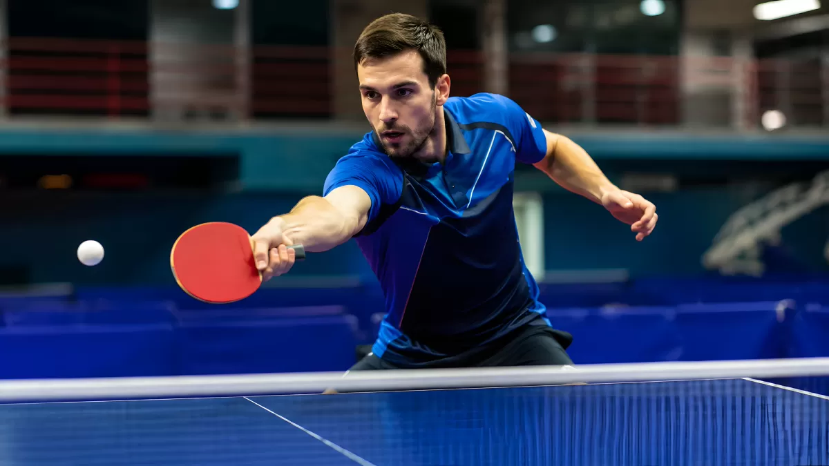 Tischtennis-Spieler schlägt Ball mit rotem Schläger