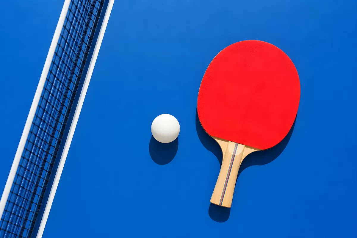 Tischtennisschläger und Ball auf blauem Spieltisch