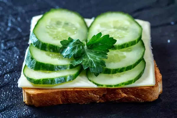 Toast with cheese and fresh cucumber on black stone