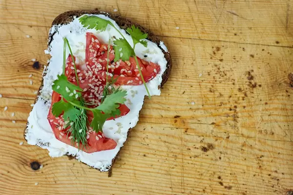 Toasted bread with sour cream, tomato slices and parsley on it