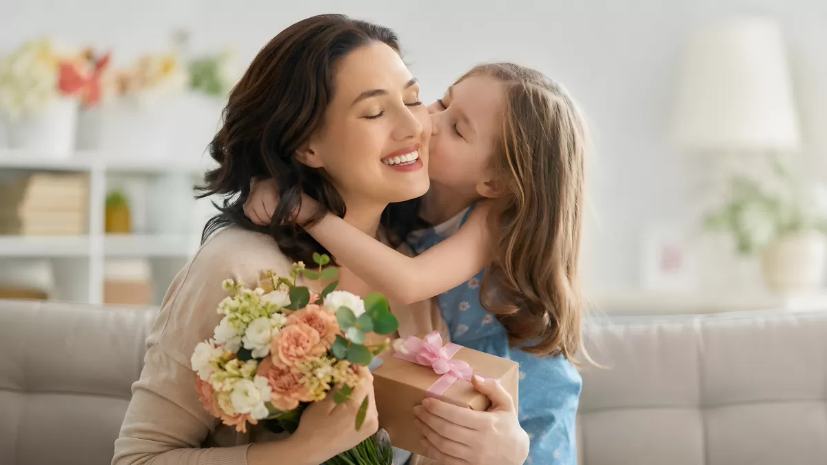 Tochter küsst Mutter mit Blumen und Geschenk