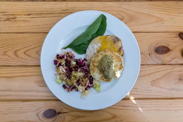 Tofu Burger made with white beans served with salad and spinach on wooden table