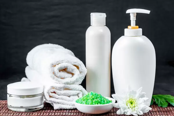 Toiletries in white with green bath salts on dark background